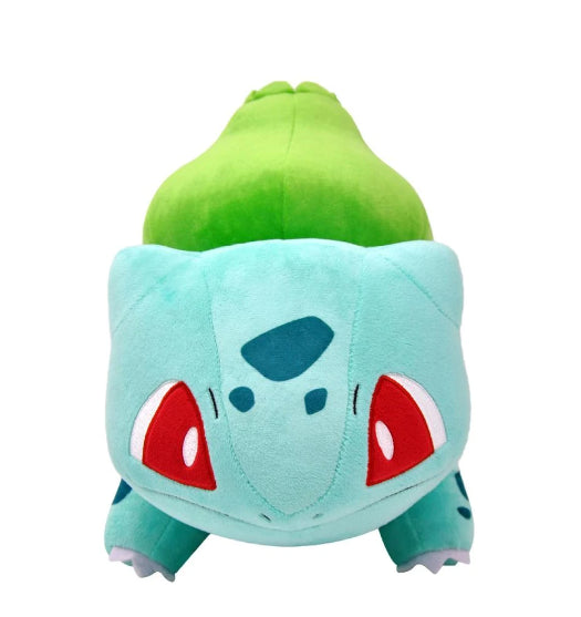 Plush toy of a green and blue creature with red eyes on a white background. Cute Bulbasaur plush looking at me