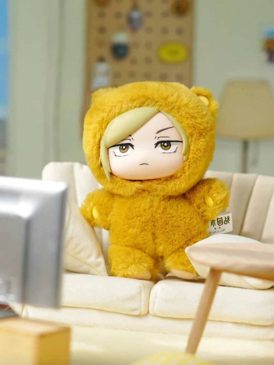Plush toy in a yellow bear costume sitting on a couch in a living room. Kento Nanami Cat Ear Plushie. Cute yellow nanami plushie