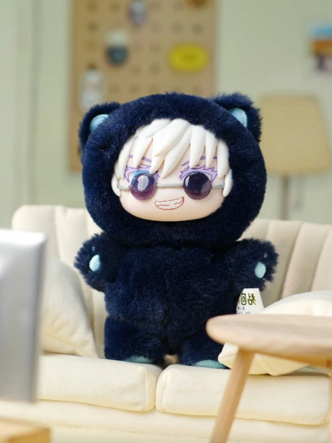 Plush toy with cartoon face sitting on a couch in a living room setting. Satoru Gojo Cat Ear Plushie