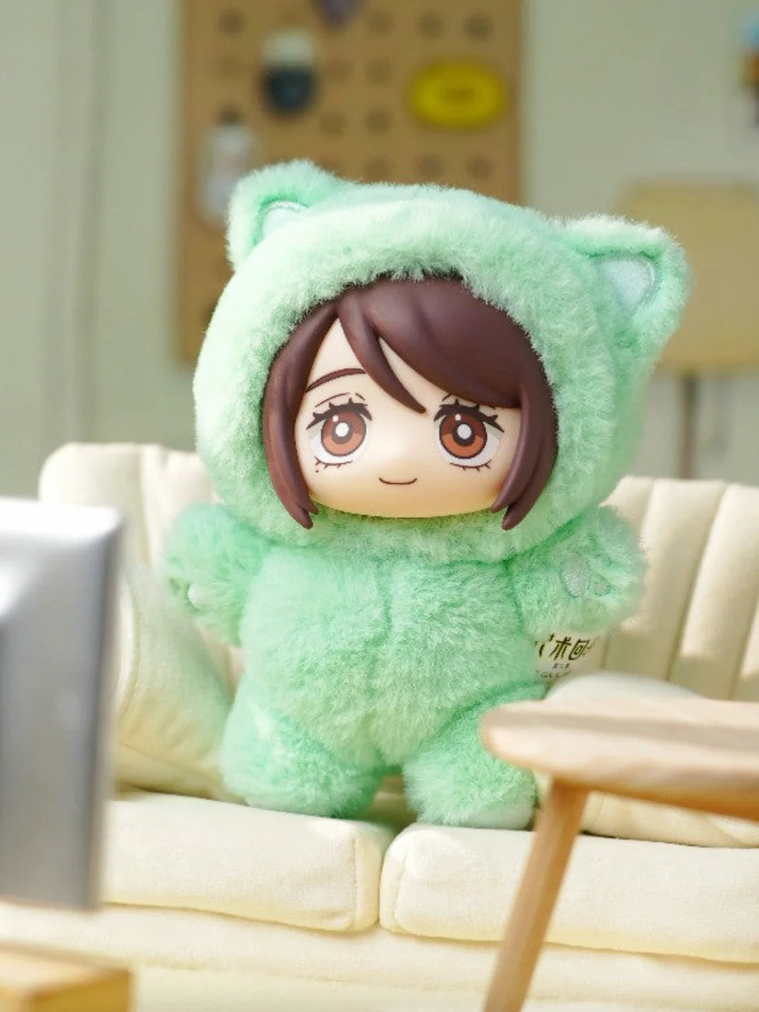 Plush toy with a character design sitting on a couch in a room. Shoko Ieiri Cat Ear Plushie. Cute green plushie Shoko